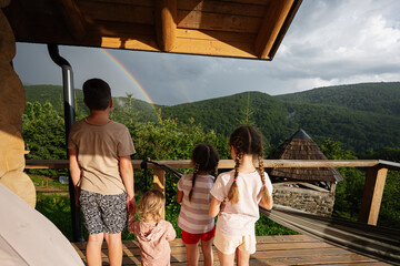Family enjoying a rainbow view from a scenic wooden deck in the mountains