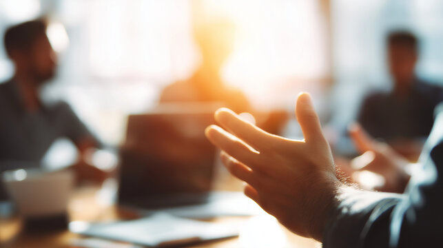 Cinematic close-up of a person's hands gesturing during a meeting, with blurred colleagues and a laptop in the background, professional DSLR photography, full HD, detailed, high-key lighting.