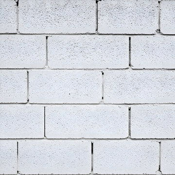 Plain white cinder block wall, exhibiting uniform texture and construction detail. Architectural view of a neutral exterior wall, showcasing construction materials.