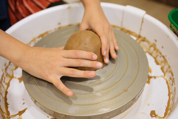 potter's wheel and girl's hands sculpting clay