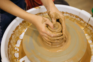 potter's wheel and girl's hands sculpting clay	