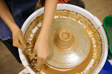 potter's wheel and girl's hands sculpting clay	