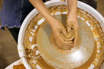 potter's wheel and girl's hands sculpting clay	