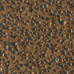 Cobblestone texture with various sized, colored stones and earth in an outdoor setting. High-angle close-up view of a gravel road surface.