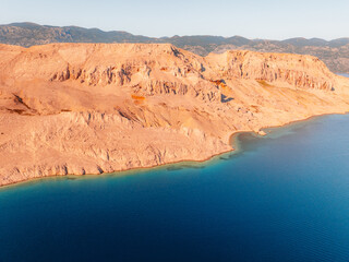 Rucica beach in Metajna on Pag island curved shoreline, crystal-clear turquoise sea, sunlit barren terrain and rocky Adriatic sea