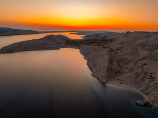 Rucica beach in Metajna on Pag island curved shoreline, crystal-clear turquoise sea, sunlit barren...