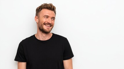 horizontal shot of handsome cheerful man looks happily away smiles broadly wears casual black t shirt isolated over white background with blank copy space being in good mood laughs at something no lo
