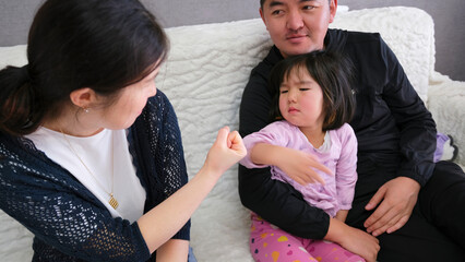 Parenting and parenting. Mom shows her daughter a fist for being guilty. A little girl sits next to...
