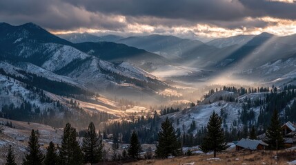 Obraz premium Sunbeams pierce a snow-dusted valley nestled between majestic mountains at sunset