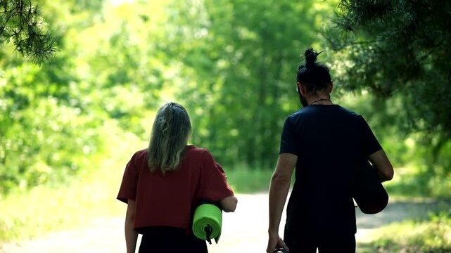Yogis Walking Along Path In Forest Holding Yoga Mats