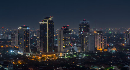 Obraz premium Panoramic nighttime vista of a vibrant urban cityscape, featuring an array of illuminated modern high-rise buildings that define the dazzling metropolitan skyline
