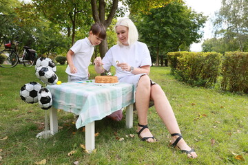 Celebrating a Joyful Birthday Party in a Serene Park With Cake, Soccer Themes, and Playful Moments Between a Mother and Son