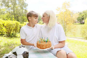 Celebrating a Joyful Birthday Moment in a Sunny Park With a Cake and Soccer Theme Surrounded by Nature and Happiness