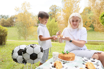 Celebrating Joy With Cake and Soccer at a Sunny Outdoor Gathering in Fall, Where a Child Shares a Sweet Moment With a Caring Adult