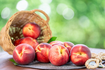 Fresh peach drop from bamboo basket on blurred greenery background, Peach fruit in Bamboo basket on wooden table in garden.