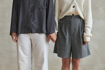 Medium section shot of two unrecognizable women in love wearing clothes matching in colors holding hands
