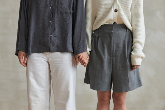 Medium section shot of two unrecognizable women in love wearing clothes matching in colors holding hands
