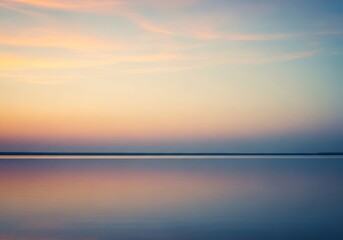 Serene landscape featuring a calm body of water reflecting a pastel-colored sky at dawn or dusk, with a soft gradient of colors.