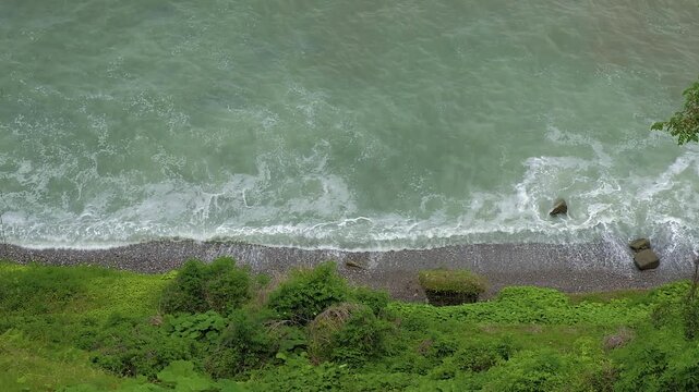 Coastal pushy waves are crashing onto green shore. Nature power