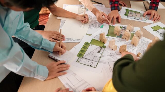 Architect and safety engineer discussion about building construction use blueprint on table with architectural document, measurement tool and wooden block scatter around at modern office. Delineation.