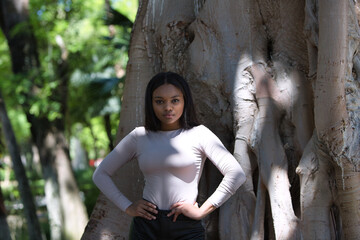 African woman, with long brown hair, young and beautiful, dressed in casual clothes with her hands...