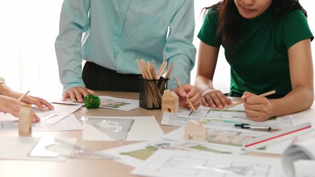 A video of architect use measurement tools and pencil to measure blueprint. Architect design house construction on a table at studio, with architectural plan scattered around. Focus hand. Delineation.