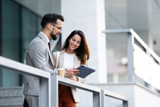 Business colleagues using tablet and discussing work outdoors