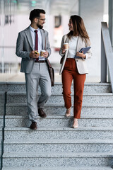 Business people walking down stairs holding coffee and tablet in modern office building © Zoran Jesic