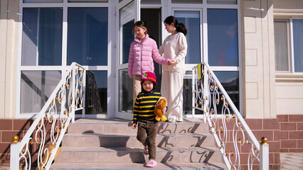A woman and two children are standing on the landing at the house. A Kyrgyz family. A single mother goes outside for a walk