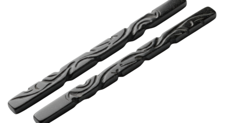 Ancient, heavy, dark polished basalt stone chopsticks, intricately carved with abstract patterns, on brilliant white studio background with copy space. Concept of meditative elegance