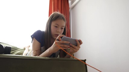 young girl playing on smartphone with headphones, concept of online gaming, youth media, digital childhood - Powered by Adobe