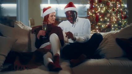 Black man and his charming Caucasian girlfriend celebrating Christmas Eve. Portrait of happy biracial lovers with glasses of champagne at home, merry Xmas party, joyful people smiling and laughing