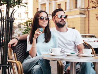 Smiling beautiful woman and her handsome boyfriend. Happy cheerful family. Couple drinking coffee in restaurant. They drinking tea at cafe in street. Holding cup. Enjoying their date. In sunglasses