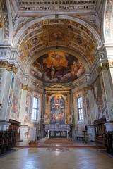 Obraz premium The elaborate interior of a historic Italian church, featuring a richly decorated altar and a magnificent vaulted ceiling covered in Renaissance frescoes.