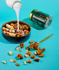 Crunchy granola topping poured into a bowl with nuts and milk