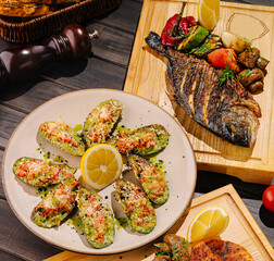 Seafood platter with grilled fish and stuffed shells on wood table