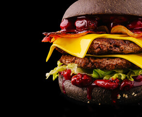 Black burger with layers of cheese, bacon, and appealing toppings