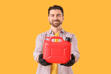 Young man with canister on yellow background