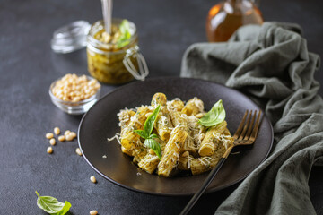Rigatoni with pesto sauce and  cheese in palte on the table