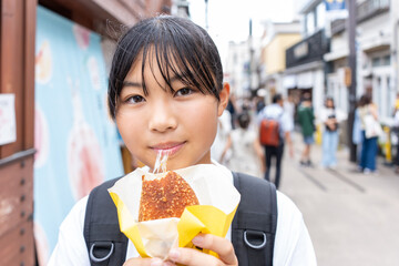 鎌倉観光をしながら食べ歩きをする10代の女性