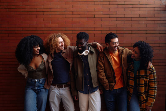 Happy students smiling and having fun together against brick wall