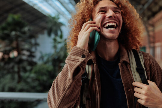 Happy tourist laughing while talking on phone in airport