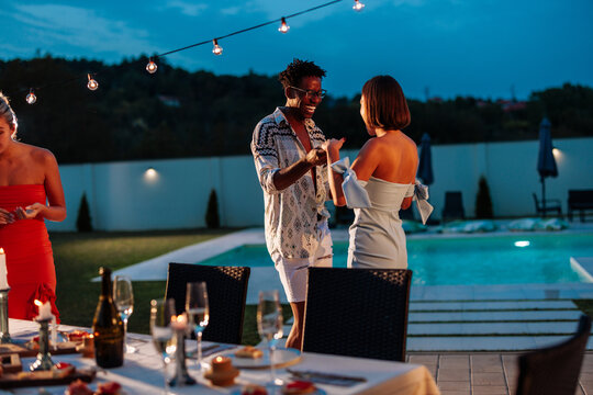Friends dancing at a pool party enjoying summer holidays