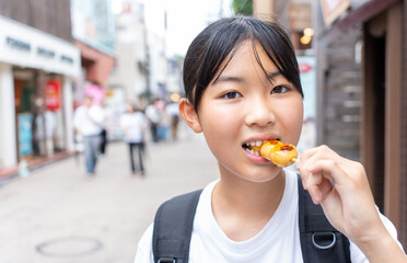鎌倉観光をしながら食べ歩きをする10代の女性