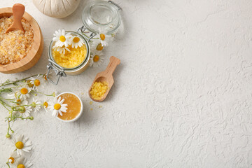 Chamomile flowers, glass jar, bowl and scoop with sea salt on grey grunge background