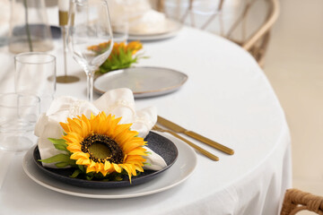 Elegant table serving with folded napkin, golden cutlery and beautiful sunflower, closeup