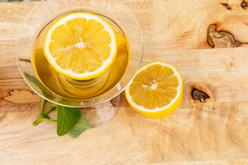Overhead shot of a warm lemon tea in a cup, neatly served on a wooden table, highlighting freshness...