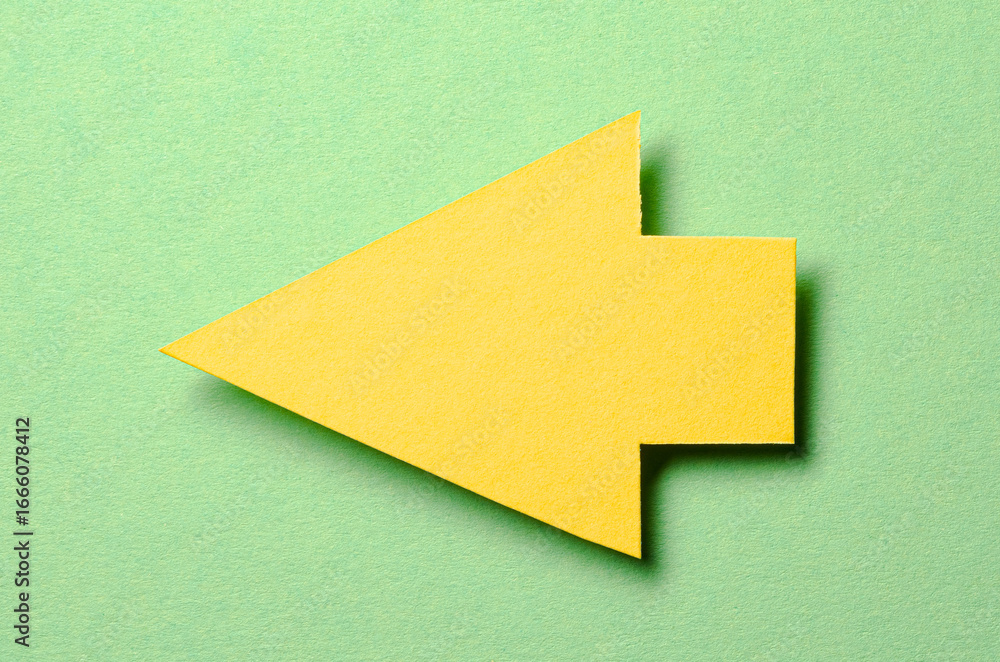 Poster yellow cut out blank paper cardboard arrow direction sign with copy space for text on green backgrou