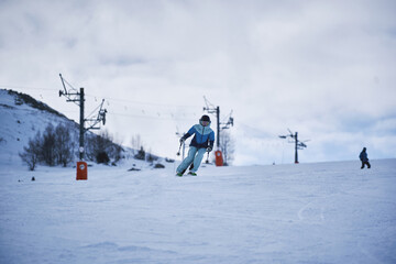 Skier carving down snowy slope at mountain ski resort with lifts in background