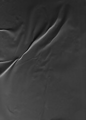 Black crumpled and creased glued paper isolated on a clean background. The textured surface adds depth and character, ideal for modern and artistic design projects. Hoja papel negro mojado.